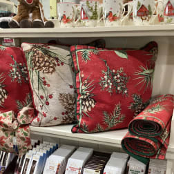 Holiday pillows and mugs with pinecone and cardinal patterns on store shelves