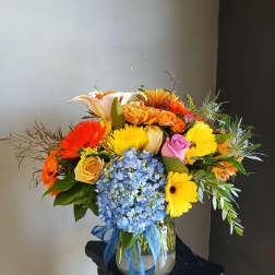 Colorful mixed bouquet in a glass vase with blue ribbon