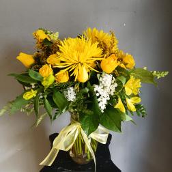 Yellow bouquet in a glass vase with a ribbon bow