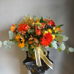 Colorful mixed bouquet in a glass vase with a gold ribbon