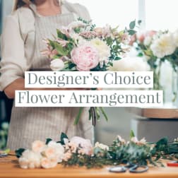 Florist in an apron holding a pastel pink and white mixed flower bouquet