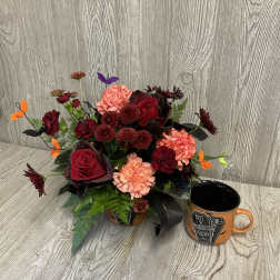 Halloween floral arrangement in an orange container with a matching mug beside it