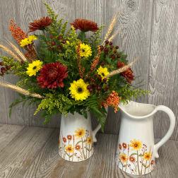 Autumn bouquet of red and yellow daisies in a white floral pitcher