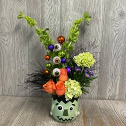 Halloween bouquet in a Frankenstein face vase with orange roses and eyeball picks