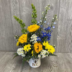 Yellow and blue flowers arranged in a bee-themed mug