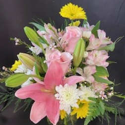 Pink lilies and roses with white daisies in a glass vase