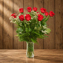 Red roses in a clear glass vase with white filler flowers
