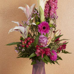 Tall mixed bouquet in a purple vase with lilies, gerbera daisies, roses, and pink snapdragons