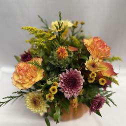Mixed bouquet of orange, yellow, and purple flowers in a vase
