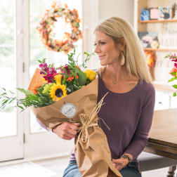 Woman holding a wrapped bouquet of mixed flowers