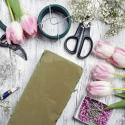 Pink tulips with floral tools and wire on a white wooden surface