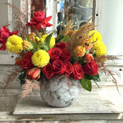 Red roses and yellow pom flowers arranged in a gray vase