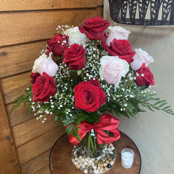 Bouquet of red and white roses in a glass vase with a red ribbon
