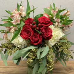 Red roses and white blooms arranged in a glass vase