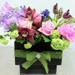 Mixed bouquet of pink roses, orchids, and purple flowers in a black box