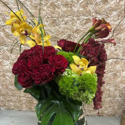 Bouquet of burgundy roses and yellow orchids in a mirrored vase