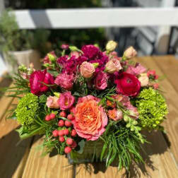 Pink and red mixed flower arrangement in a square container