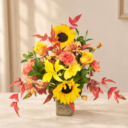 Yellow sunflowers and mixed blooms in a square metal vase