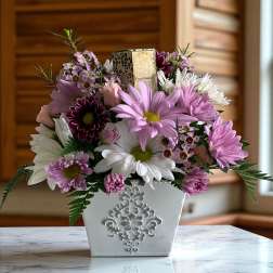 Pink and white daisy bouquet in a white decorative container