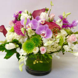 Mixed bouquet of orchids, roses, and chrysanthemums in a glass vase
