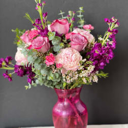 Pink and purple bouquet in a magenta glass vase