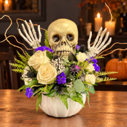 Skull centerpiece with cream roses and purple flowers in a white pumpkin vase