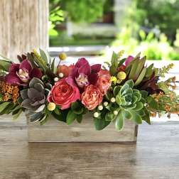 Low floral centerpiece in a rectangular wooden box with pink and burgundy blooms