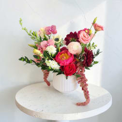 Mixed pink and burgundy flowers in a white ribbed vase