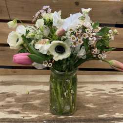 Mixed white and pink flowers arranged in a glass jar vase