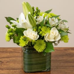 White lilies and roses in a green glass vase
