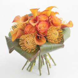 Orange roses and calla lilies with yellow pincushion blooms in a hand-tied bouquet