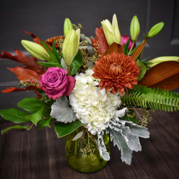 Mixed bouquet with lilies, roses, hydrangea, and chrysanthemum in a green glass vase