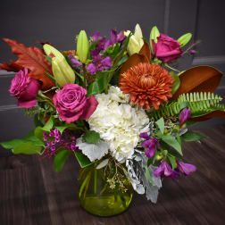 Mixed bouquet with purple roses, white hydrangea, and orange chrysanthemum in a green vase