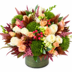 Peach and white roses in a green round vase with bright green moss balls