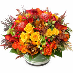 Bright mixed bouquet of yellow and orange roses in a round vase