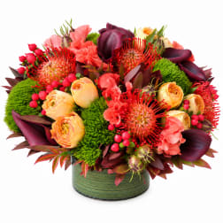 Bright mixed bouquet in a green round vase with red and peach blooms