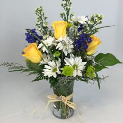 Yellow roses and white daisies in a glass vase with blue flowers