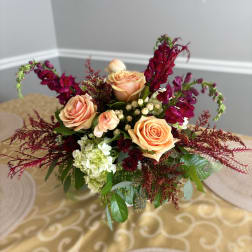 Peach roses with burgundy flowers in a low arrangement