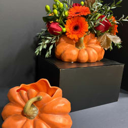 Orange pumpkin centerpiece with red roses and orange gerbera daisies