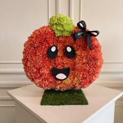 Pumpkin-shaped floral arrangement with a face and black ribbon bow
