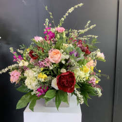 Large mixed bouquet with pink, red, white, and yellow flowers in a square vase