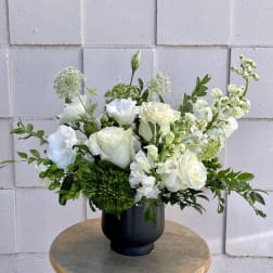 White roses and white blooms arranged in a black vase