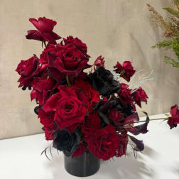 Red and black rose arrangement in a black vase