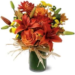 Orange and red mixed bouquet in a green glass vase