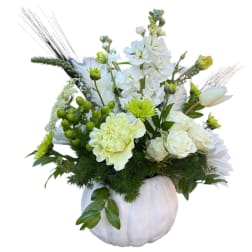 White floral arrangement in a white pumpkin vase with green accents