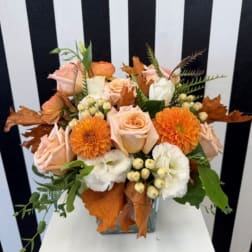 Peach and orange floral arrangement in a clear glass vase