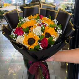 Bouquet of sunflowers, red and white roses, and baby's breath wrapped in black paper