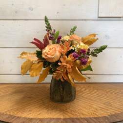 Autumn bouquet of peach and purple flowers in a dark glass vase