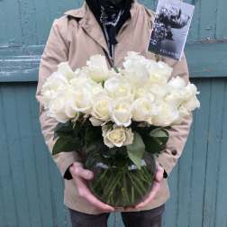 Person holding a vase of white roses