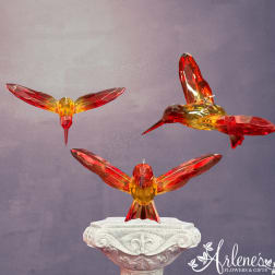 Three crystal hummingbird figurines on a decorative pedestal